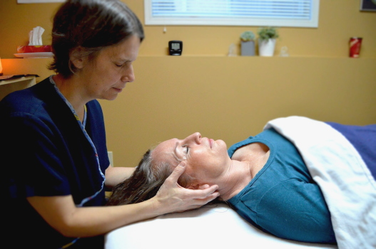 A craniosacral therapist working on a prone client