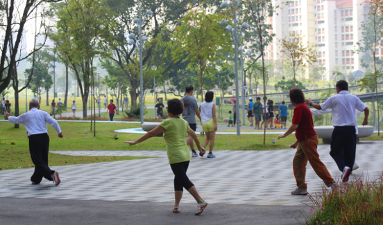 People practising tai chi outdoors in a park.