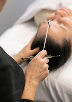 Aimee Sebastian using a reflexology tool on a client's forehead