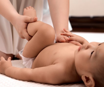 A baby lying on its back receiving massage. 