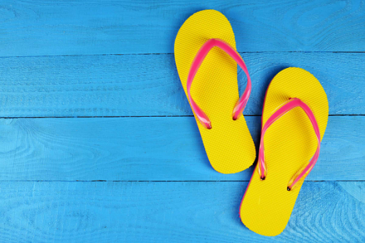 Yellow and pink flip-flops on a summery blue background. 