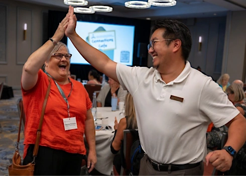 Two staff membes high-fiving at a Connections Cafe