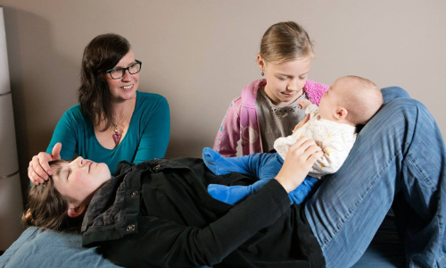 A mother, daughter, and baby in a craniosacral therapy session together