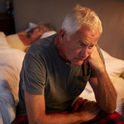 Man sitting on the edge of the bed unable to sleep.