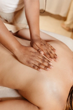 A massage therapist lays hands on a client's back. 