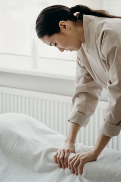 A massage therapist working on a client's draped leg through the sheet. 