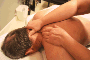 NHPC massage therapist works on client's neck while they are face-down