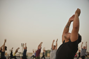 An outdoor yoga class with arms raised