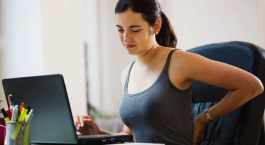 Woman with sore back sitting at computer.