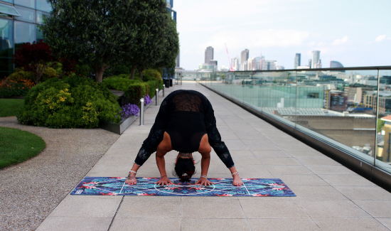 Yoga practitioner in a wide-leg forward fold on an urban terrace. 